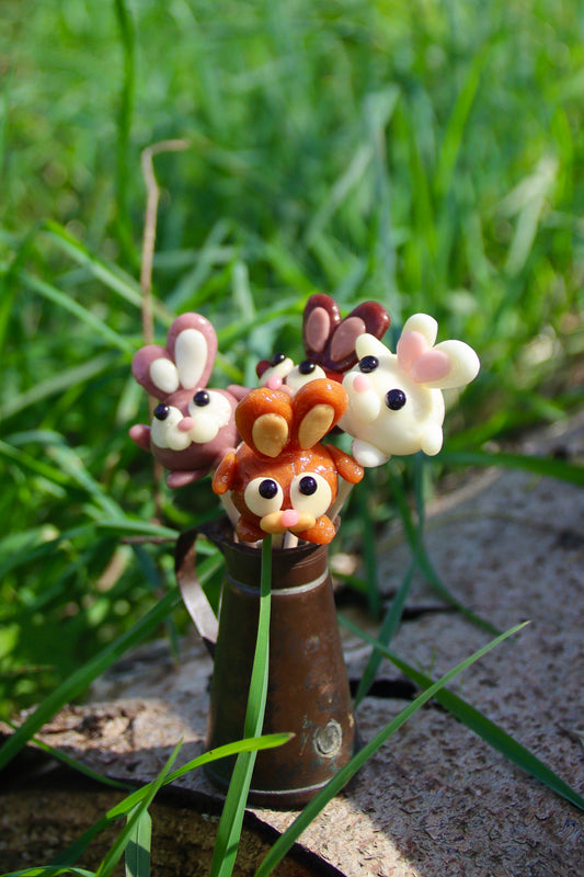 Bouquet de sucettes artisanales en forme de lapin, rassemblées dans un petit pot, réalisé à la main avec différents parfums de saison, présenté comme une création gourmande et décorative.