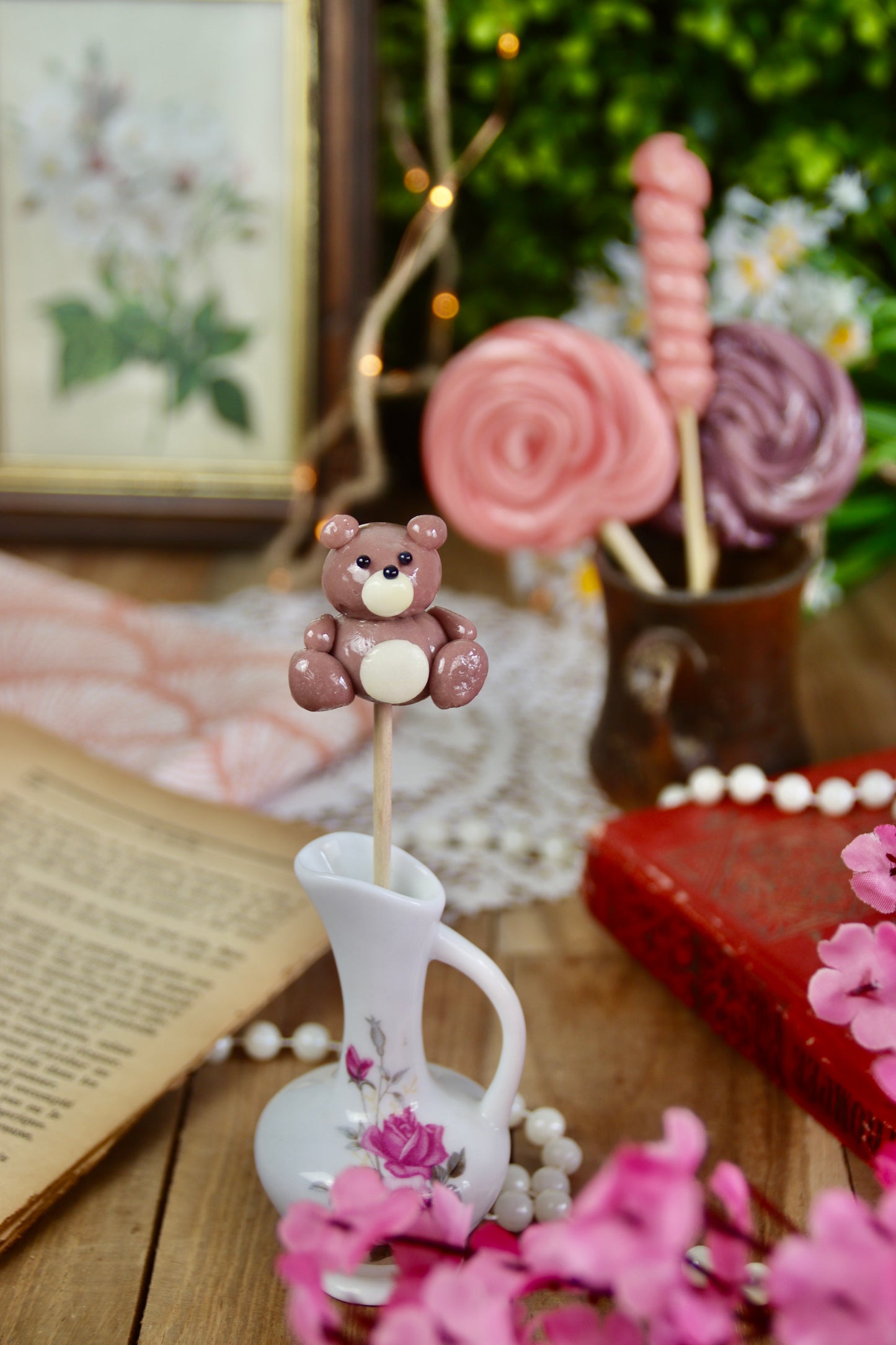 Sucette peluche violette-citron mise en scène dans un décor fleuri aux teintes pastel, évoquant l’univers tendre et gourmand de l’enfance.
