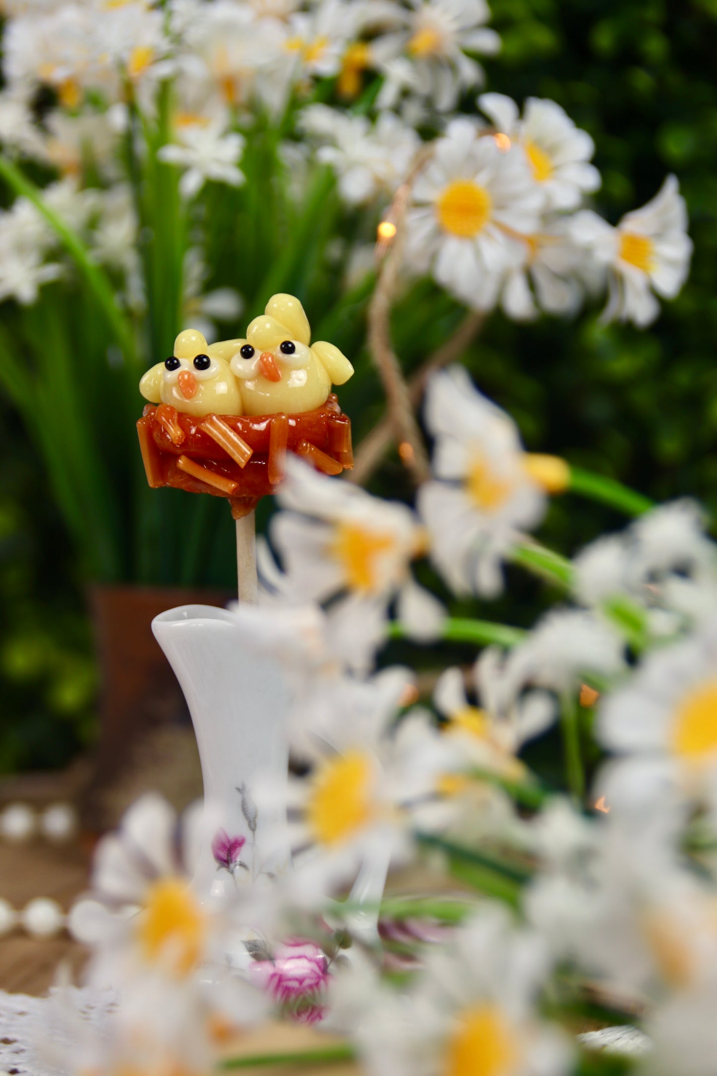 Sucette artisanale sculptée représentant deux petits poussins à la pêche, nichés dans un nid au caramel beurre salé. Une création minutieuse et gourmande, parfaite pour célébrer le printemps et Pâques.