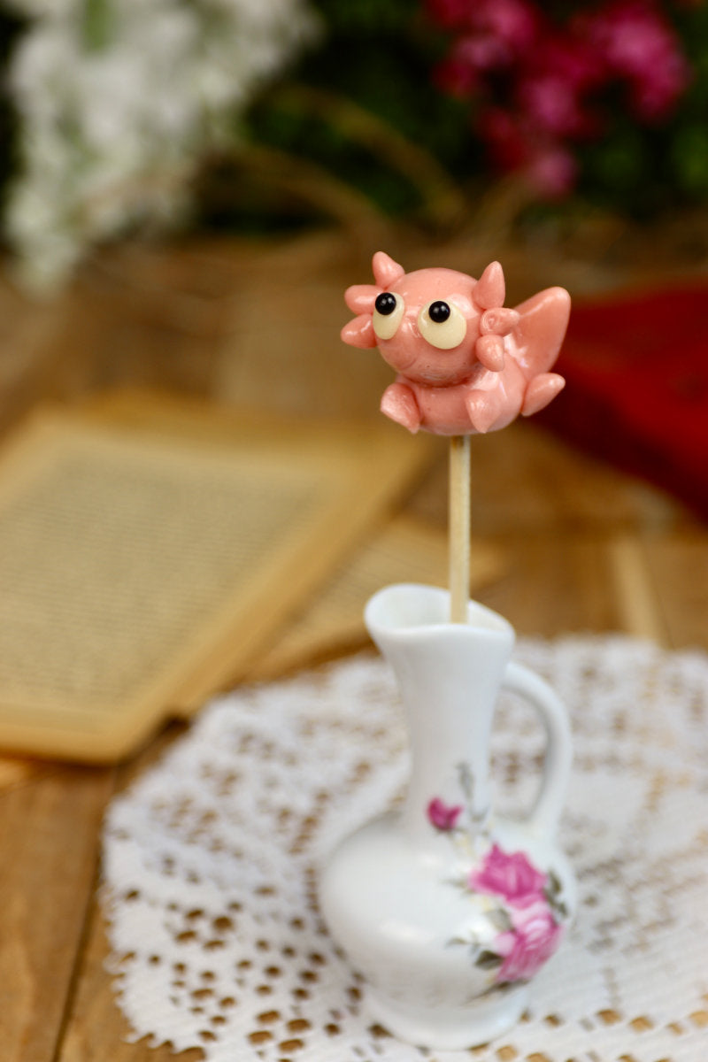 Sucette axolotl framboise présentée dans un décor marin enchanté