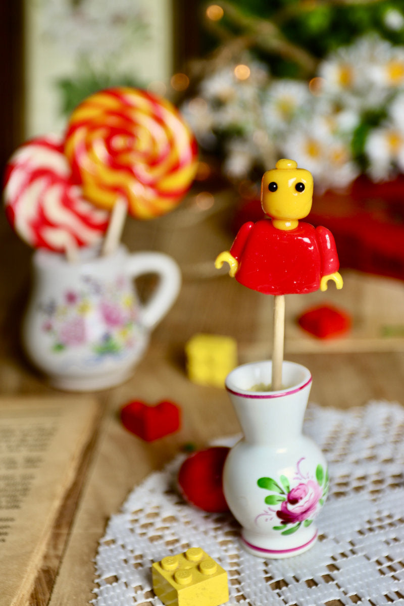 Sucette légo posée dans un décor coloré et joyeux, évoquant l’univers des jouets et de l’enfance.