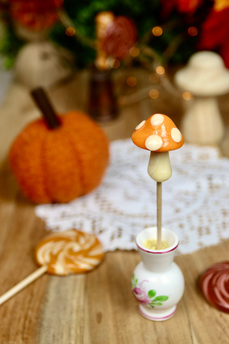 Sucette champignon vanille orange présentée dans une ambiance chaleureuse et gourmande