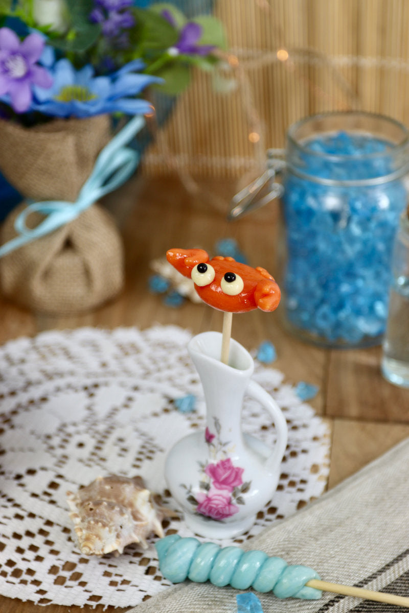 Une sucette en forme de crabe à l'orange dans un décor océan