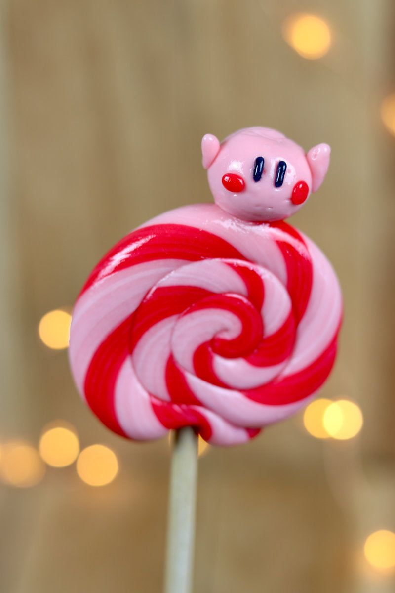 Sucette foraine à la fraise avec un Kirby à la fraise sculptée en sucre cuit dessus