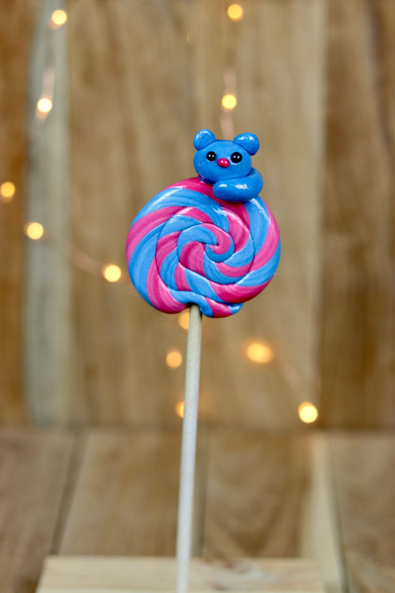 Une sucette foraine artisanale à la myrtille et à la cerise avec un chat sculptée dessus
