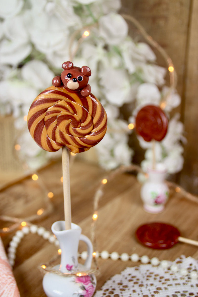 Sucette foraine peluche cacao–caramel beurre salé dans un décor féérique