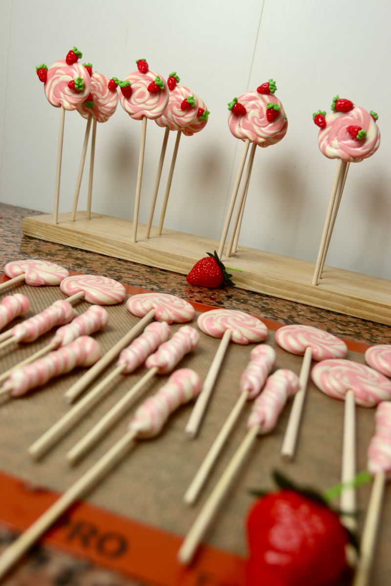 Des Sucettes foraine Ă la vanille et Ă la fraise en cours de production sur le plan de travail dans l'atelier.