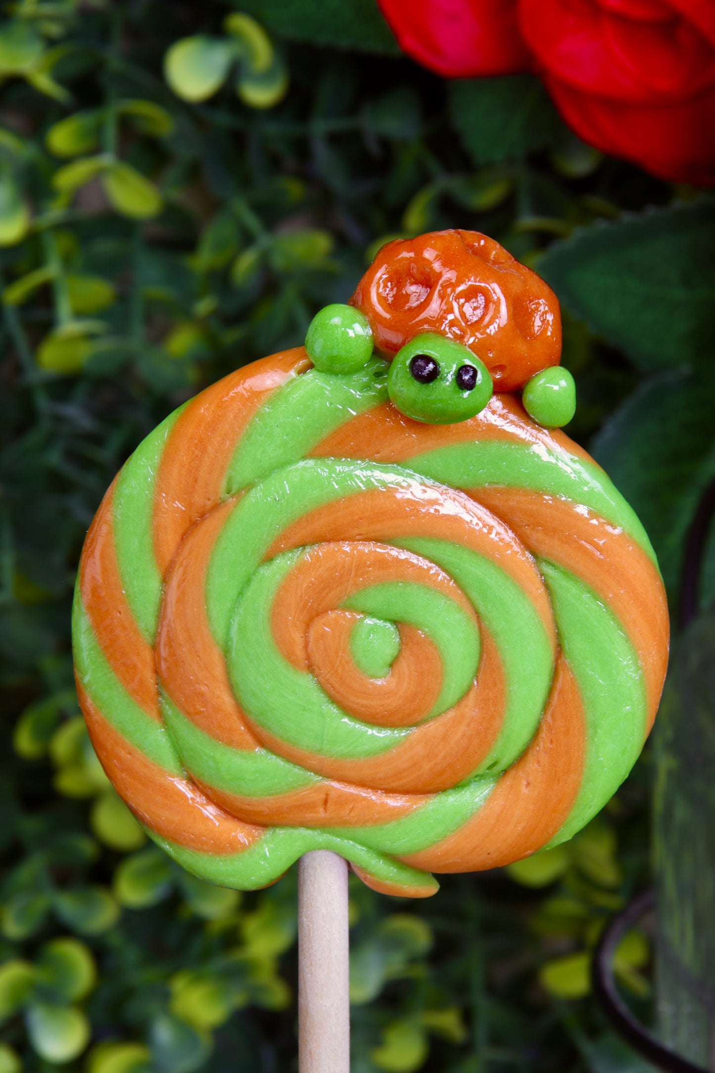Sucette foraine en spirale avec une tortue sculptée à la main, au goût pomme et caramel, présentée sur un fond marin.