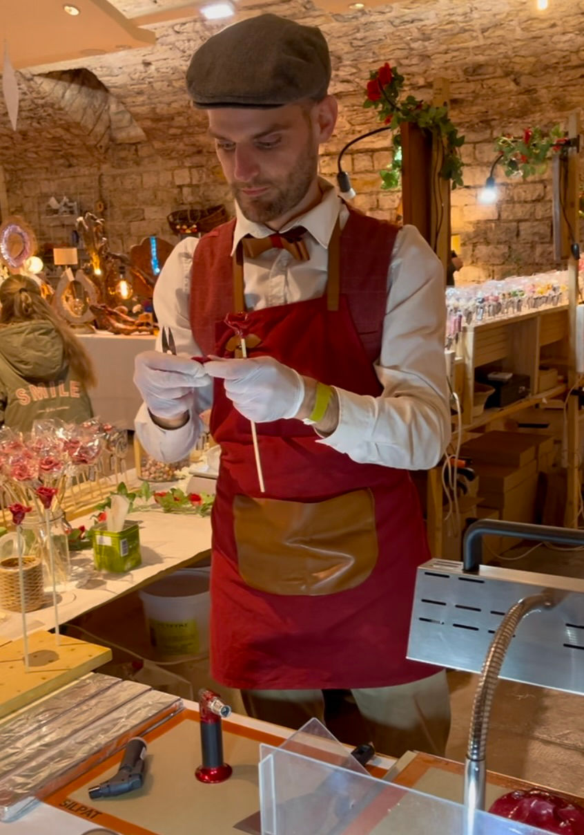 Fabrication de sucette en forme de fleur, dans un endroit champêtre en pierre. 