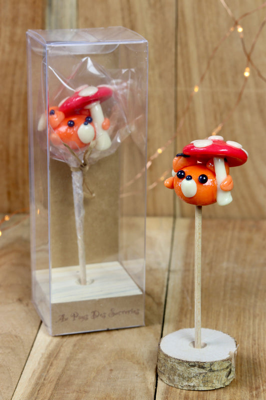 Une sucette sculptée en forme renard tenant un Parapluie en forme de Champignon Pêche Cerise. 