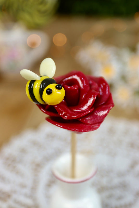 Sucette artisanale en forme de rose au cassis avec une petite abeille citron-cassis sculptée à la main