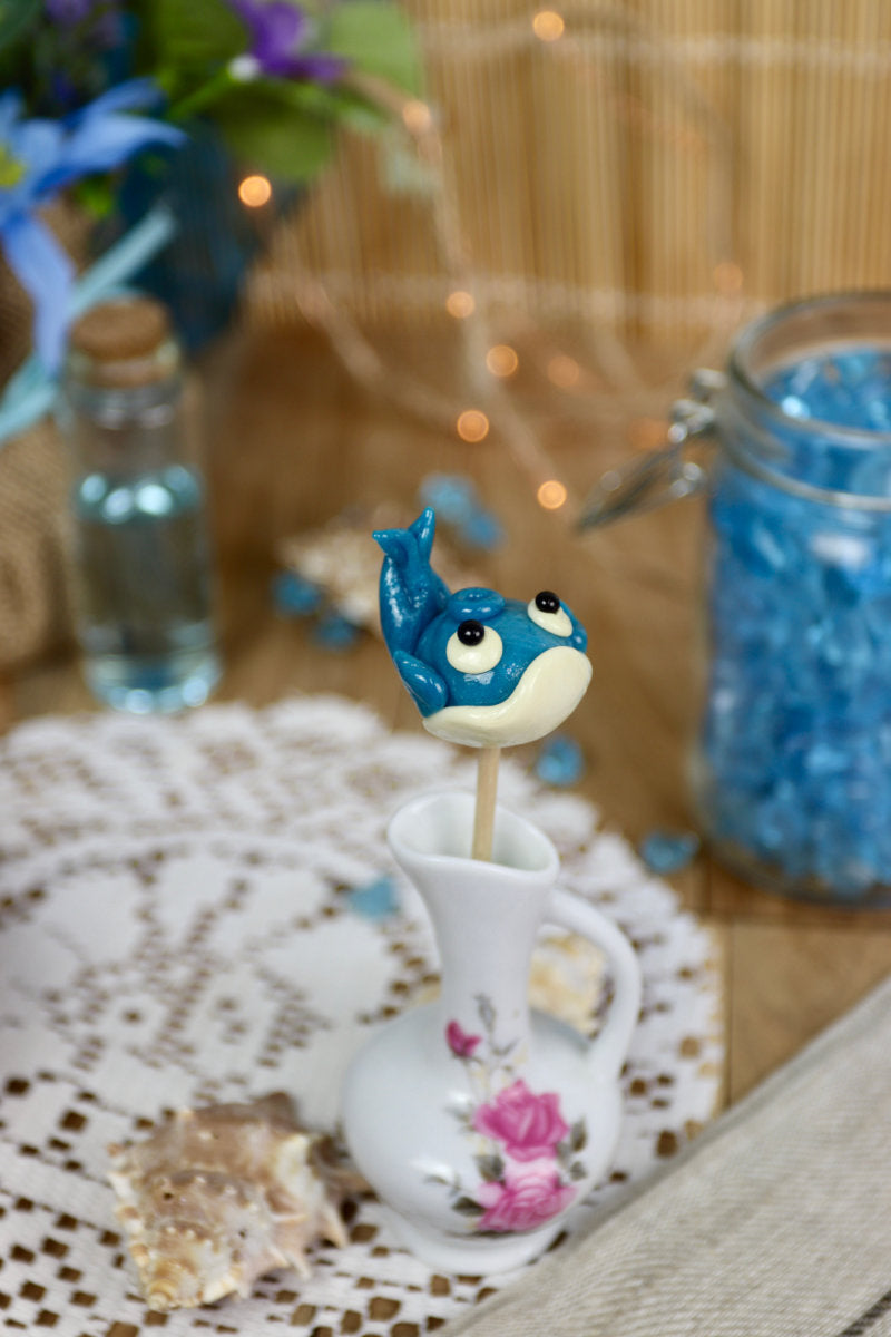 Sucette baleine myrtille-citron dans un décor marin, entourée de coquillages et d’éléments océaniques, parfaite pour une ambiance gourmande et enchantée.