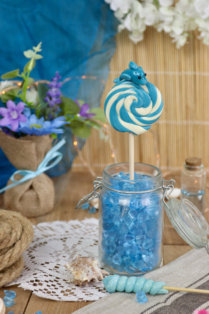Sucette foraine dauphin myrtille-citron dans un décor marin, rappelant les vagues de l’océan, parfaite pour une décoration de table à thème.