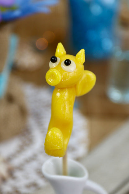 Sucette artisanale en forme d’hippocampe, sculptée à la main, au goût pêche, présentée sur un fond marin décoratif.