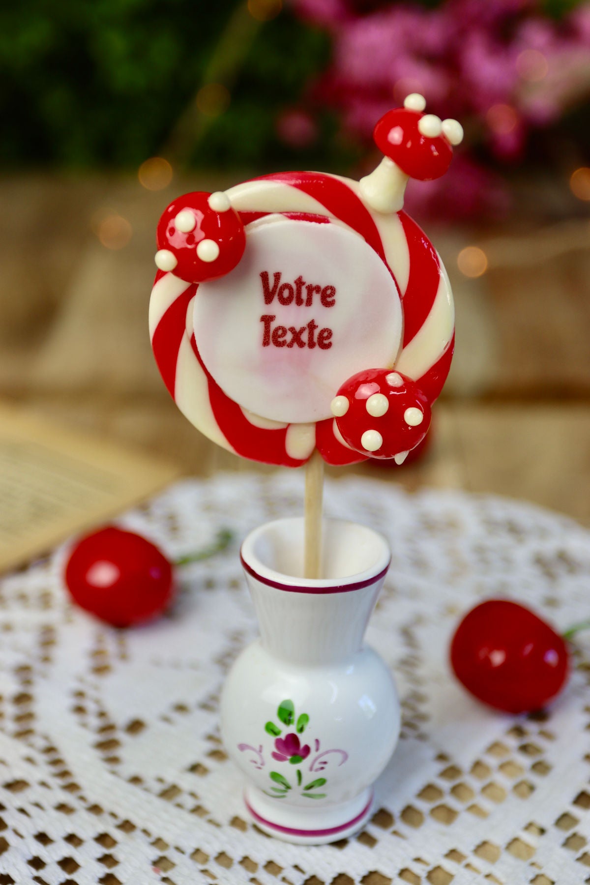 Gros plan sur une sucette personnalisée vanille cerise avec trois petits champignons rouges et blancs sculptés