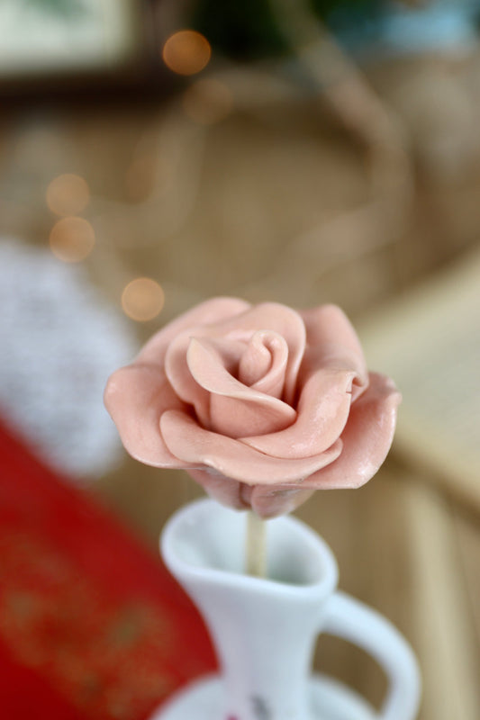 Gros plan sur une sucette artisanale en forme de rose, sculptée à la main avec un parfum de framboise. Les pétales détaillés rappellent l’élégance d’une fleur fraîche.