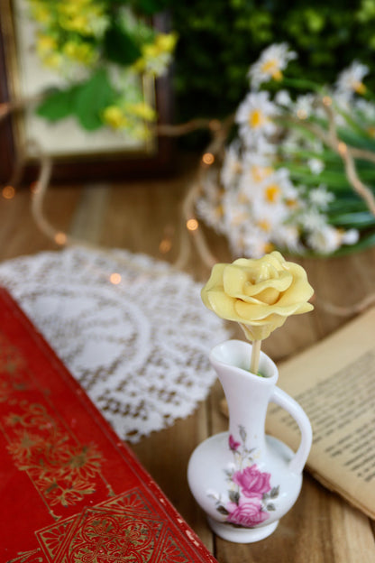 Sucette fleur à la pêche, présentée dans un décor printanier, parmi des fleurs naturelles et des objets de fête.
