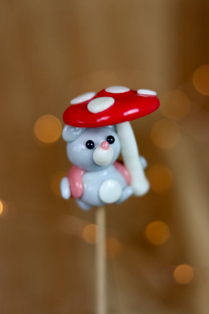 Sucette sculptée en forme de souris habillé d'un gilet à la framboise qui tient un parapluie en forme de champignon au citron et à la framboise