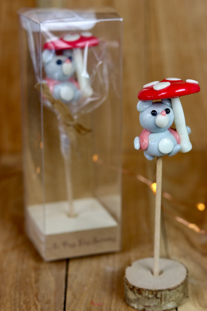 Sucette sculptée en forme de souris habillé d'un gilet à la framboise qui tient un parapluie en forme de champignon au citron et à la framboise