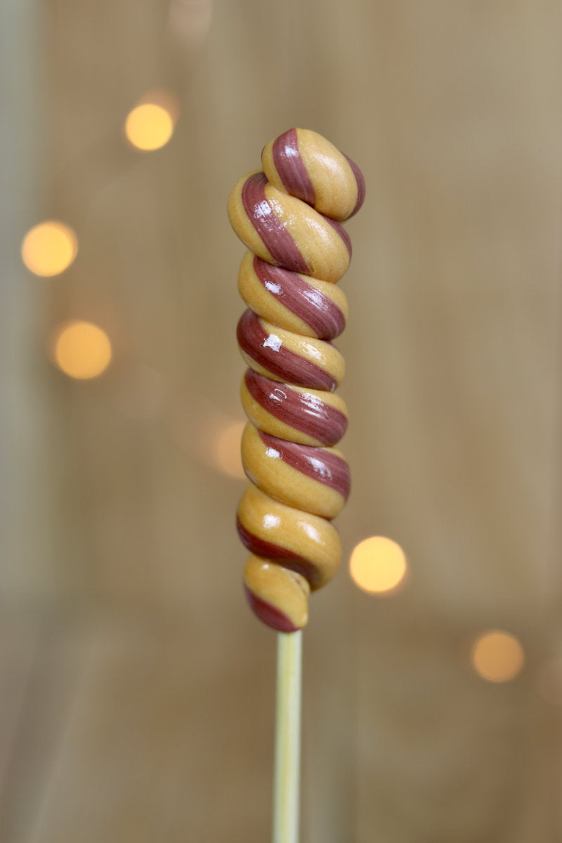 Une sucette torsade artisanale au caramel beurre salé et cacao, fabriquée dans notre atelier en Bourgogne