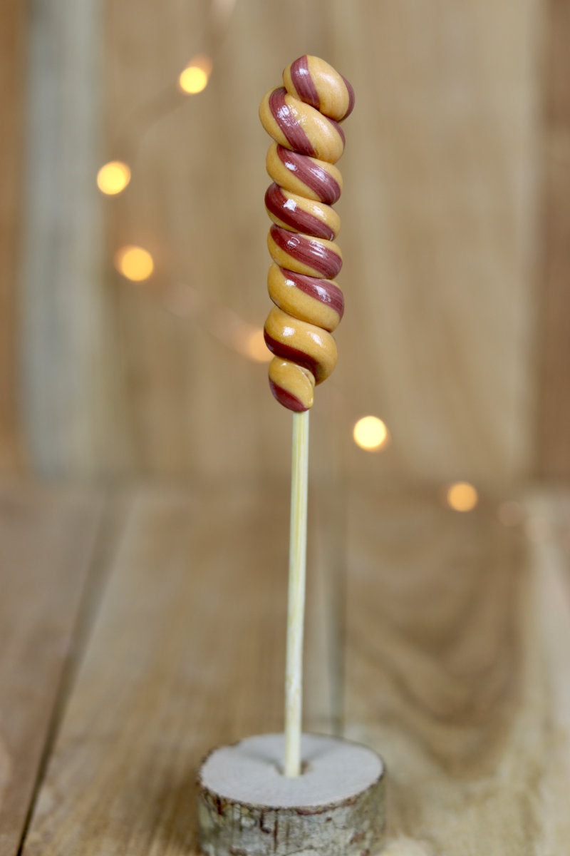 Une sucette torsade artisanale au caramel beurre salé et cacao, fabriquée dans notre atelier en Bourgogne