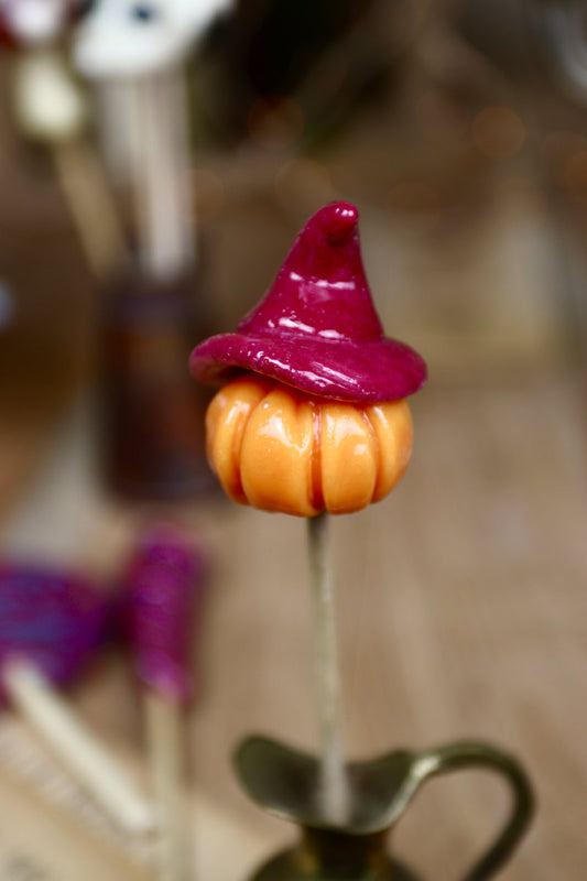 Sucette artisanale en forme de citrouille orange coiffée d’un chapeau de sorcière noir et violet – saveurs orange et cassis.