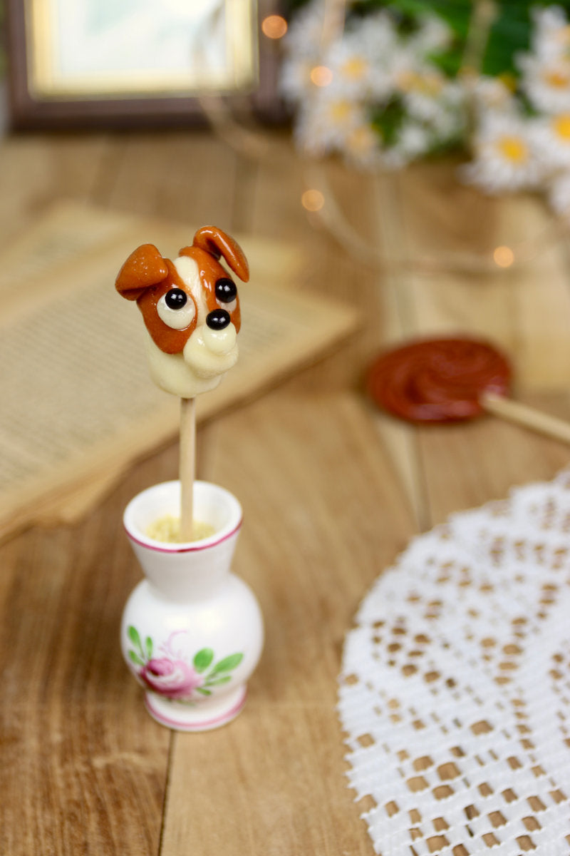 Sucette Jack Russell Vanille-Caramel présentée dans un décor chaleureux, évoquant l’univers champêtre et artisanal.