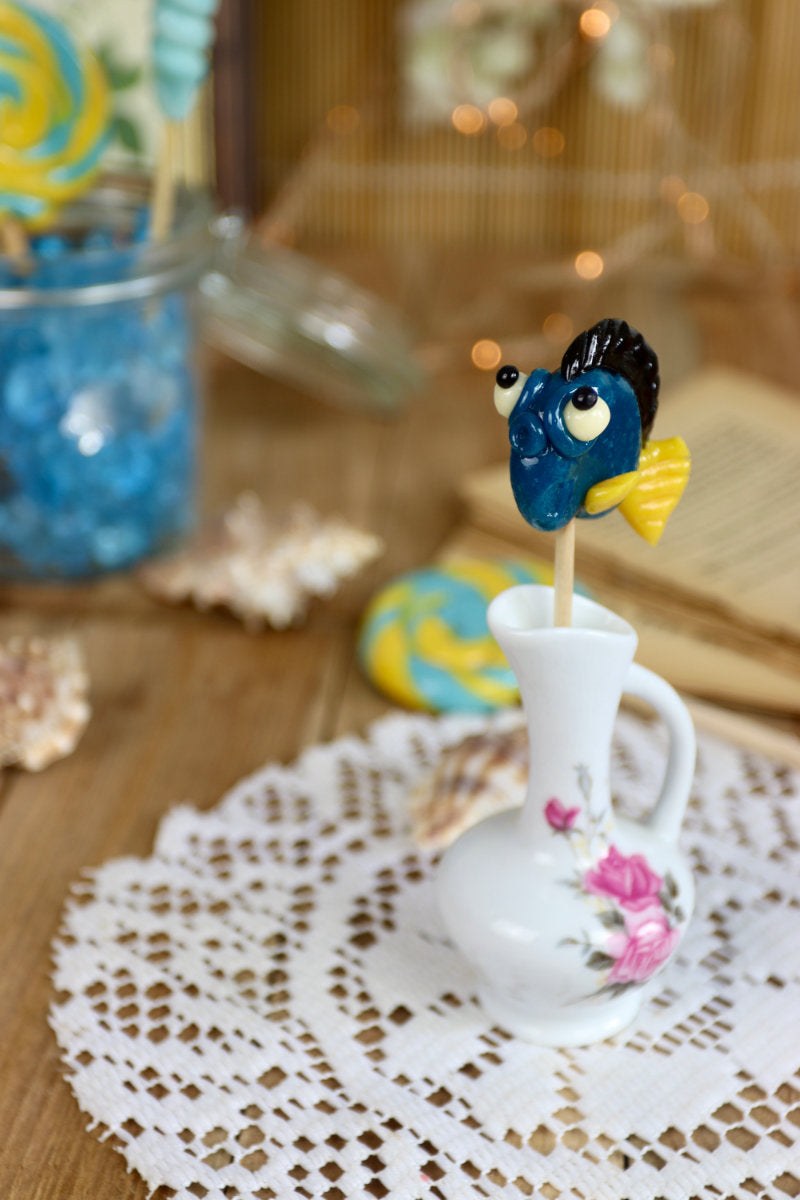 Sucette poisson posée dans un décor marin féerique, évoquant l’univers tropical et enchanté d’une confiserie artisanale.