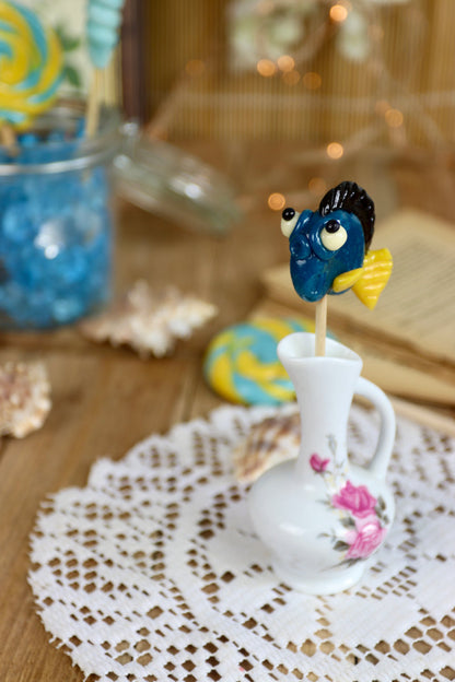 Sucette poisson posée dans un décor marin féerique, évoquant l’univers tropical et enchanté d’une confiserie artisanale.