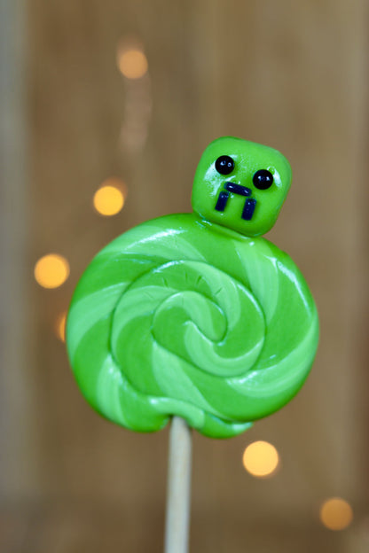 Une sucette sculptée foraine avec u ne tête de creeper. Elle est à la pomme. Idéal pour un cadeau Minecraft