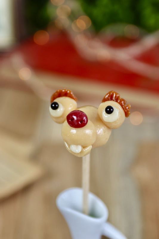 Sucette en forme de paresseux, sculptée à la main, au goût vanille et cola, avec une expression amusante inspirée d’un personnage de dessin animé.