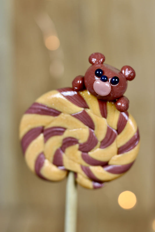 Une sucette foraine caramel beurre salé cacao avec une peluche sculptée dessus, au cacao