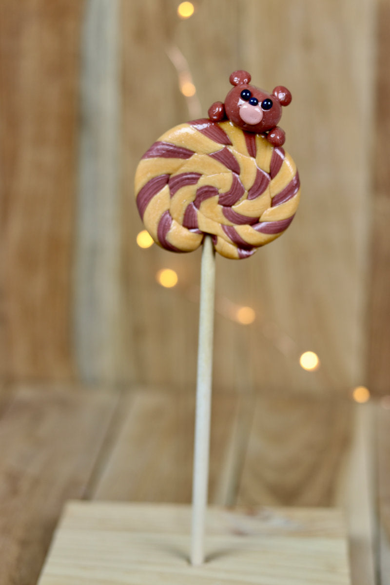 Une sucette foraine caramel beurre salé cacao avec une peluche sculptée dessus, au cacao
