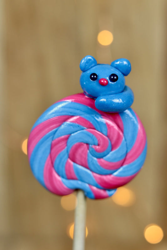 Une sucette foraine artisanale à la myrtille et à la cerise avec un chat sculptée dessus