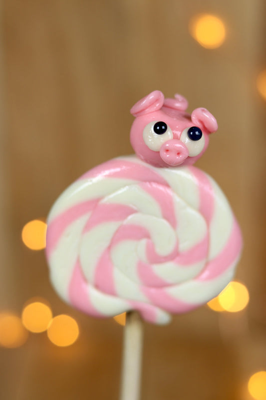 Sucette foraine artisanale vanille fraise avec un cochon sculptée en sucre cuit à la fraise dessus