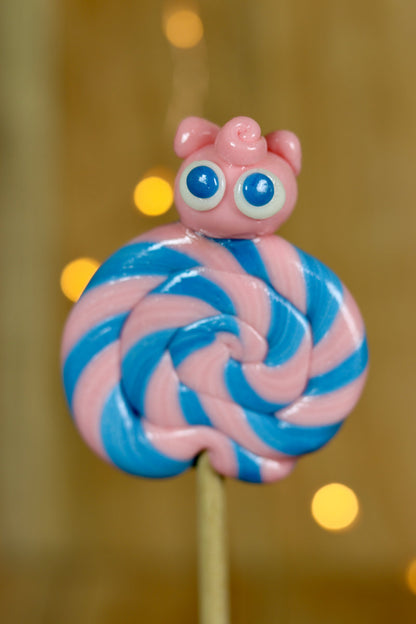 Une sucette foraine artisanale fraise myrtille avec un roudoudou sculptée dessus à la fraise