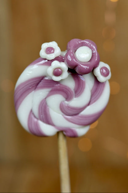 Sucette traditionnelle de forain avec des fleurs dessus à la violette et au citron