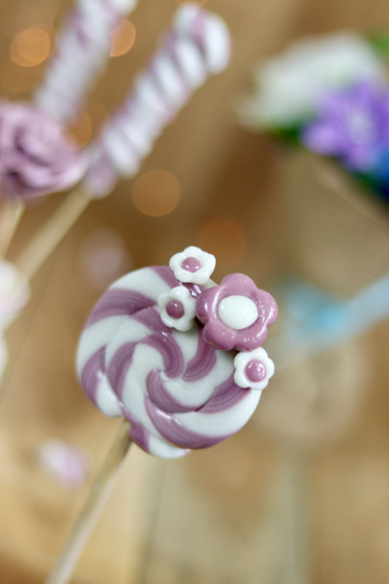 Sucette traditionnelle de forain avec des fleurs dessus à la violette et au citron