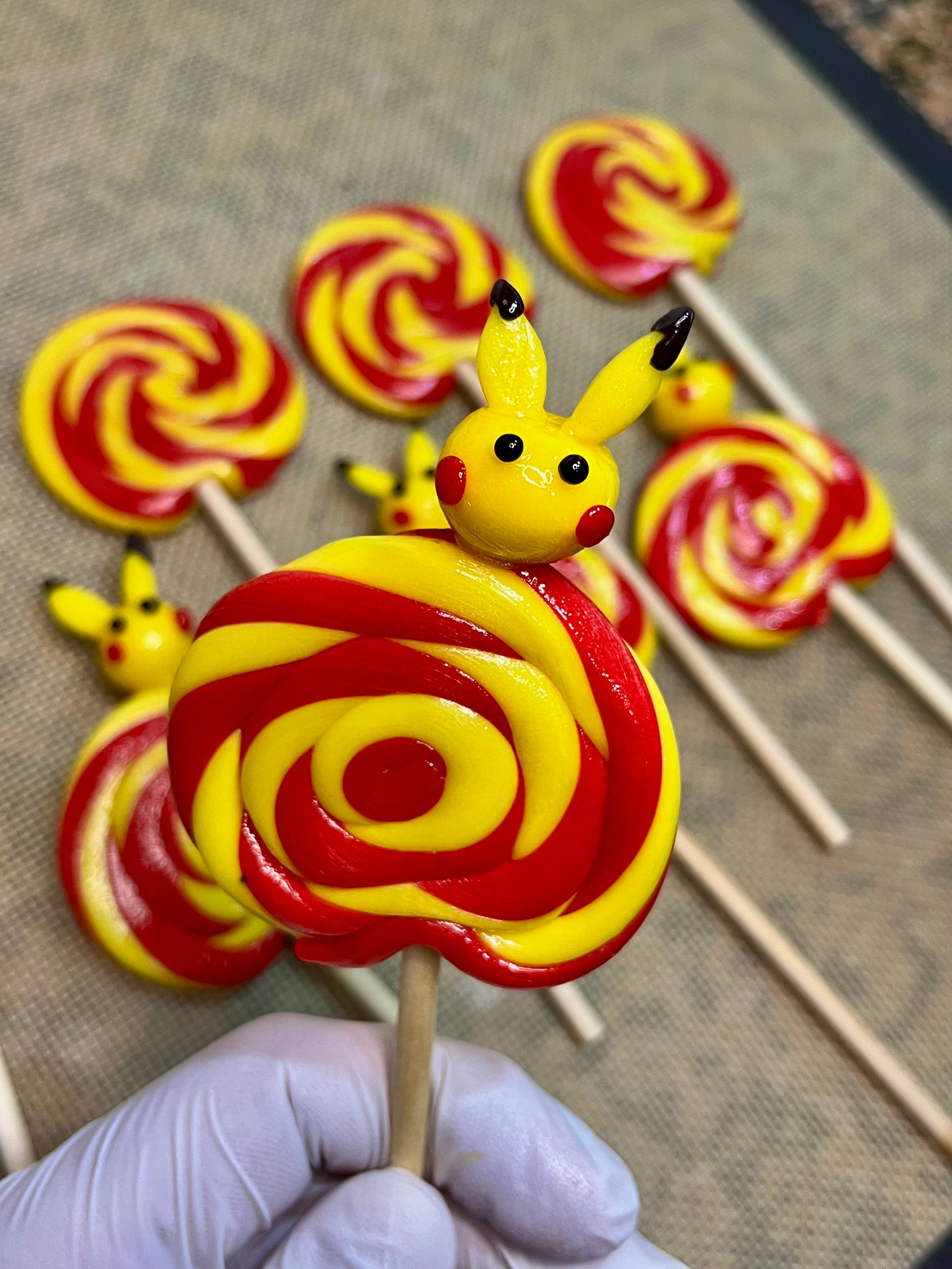 Sucette foraine banane cerise avec un pikachu sculptée à la banane dessus dans l'atelier de production
