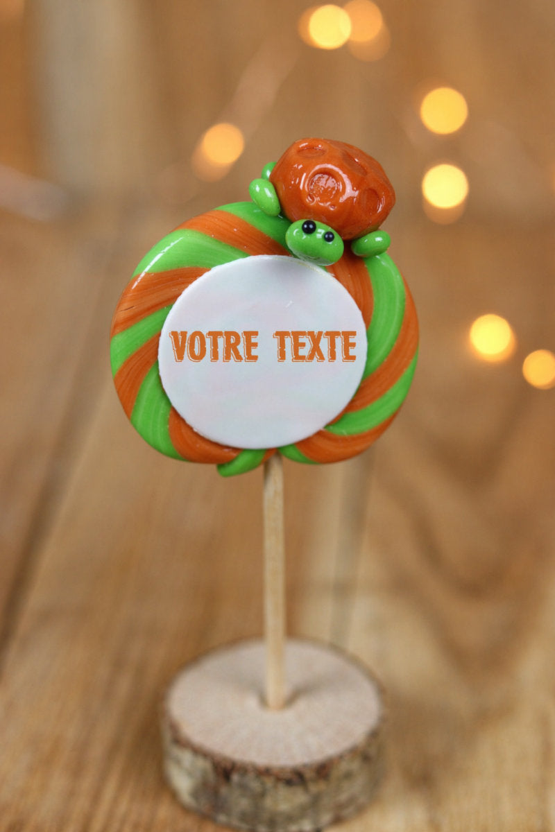 sucette imprimée à personnalisée à la pomme et au caramel avec une tortue sculptée en sucre cuit dessus dans un décor féérique