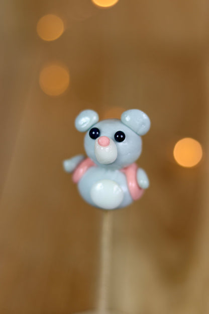 Une sucette sculptée en forme de souris qui porte un petit gilet. Au citron et à la framboise