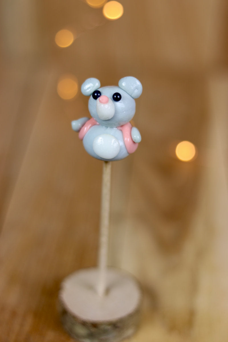 Une sucette sculptée en forme de souris qui porte un petit gilet. Au citron et à la framboise