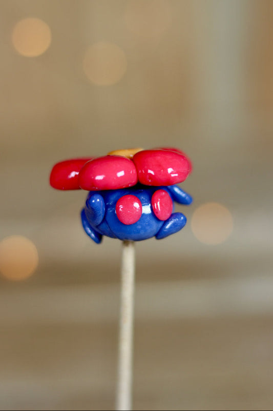 Sucette sculptée en forme du Pokémon rafflésia à la myrtille et à la cerise. 