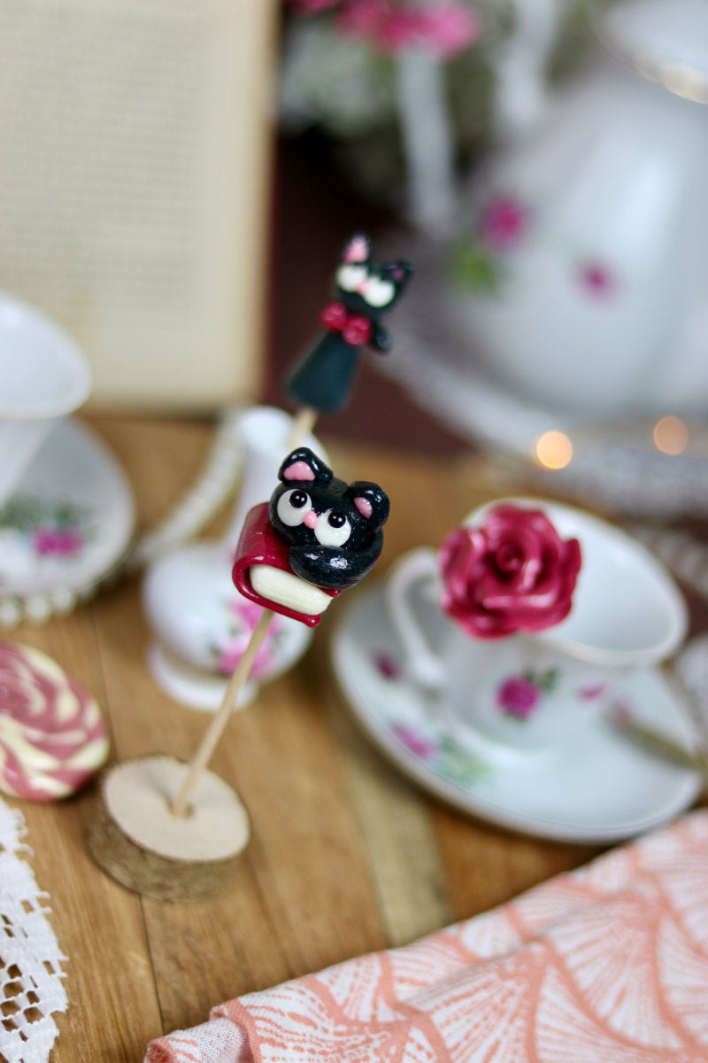 Sucette en forme de chat posé sur un livre au cassis dans un déco élégant