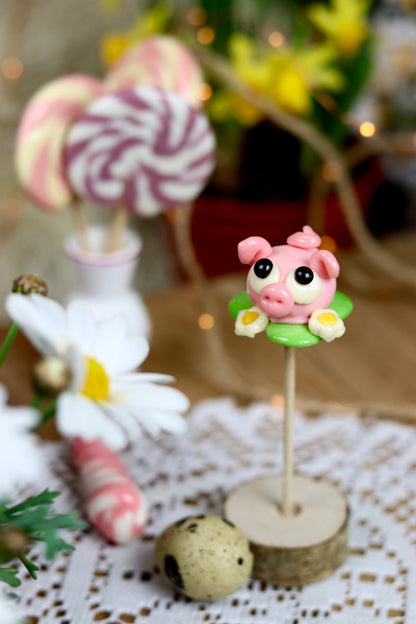 Sucette sculptée en forme de cochon dans une prairie dans un déco printanier