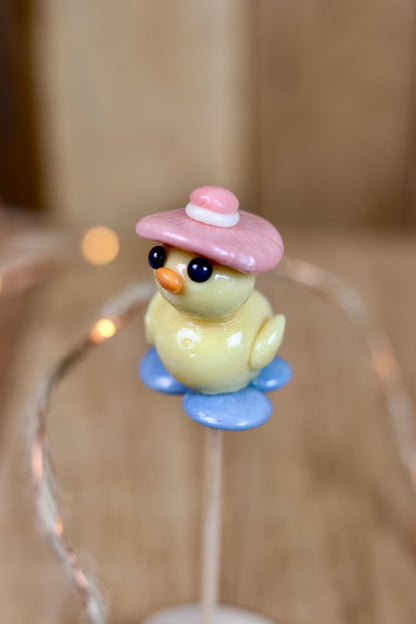 Une sucette sculptée en forme de canard à la pêche sur l'eau à la myrtille avec un chapeau sur la tête à la framboise