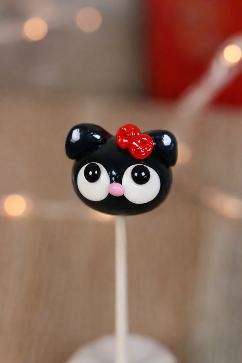 Une sucette sculptée en forme de tête de chat dans un style kawaii au cassis