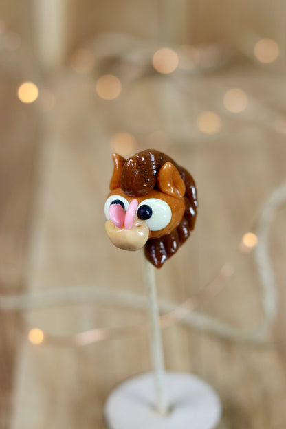 Sucette scullptée en forme de cheval au caramel avec un papillon sur son nez. Sucette en sucre cuit
