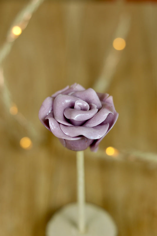 Sucette artisanale sculptée en de fleurtype rose à la violette en sucre cuit. 