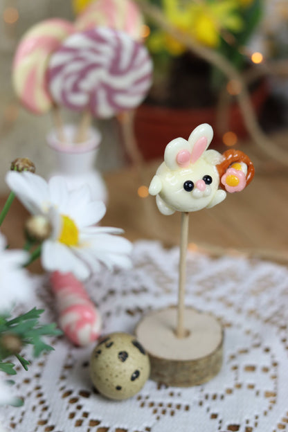 Sucette sculptée en forme de lapin à la banane qui porte un panier de fleur dans un décor printanier